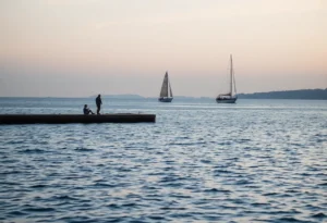 A tranquil waterfront scene with a vintage sailboat